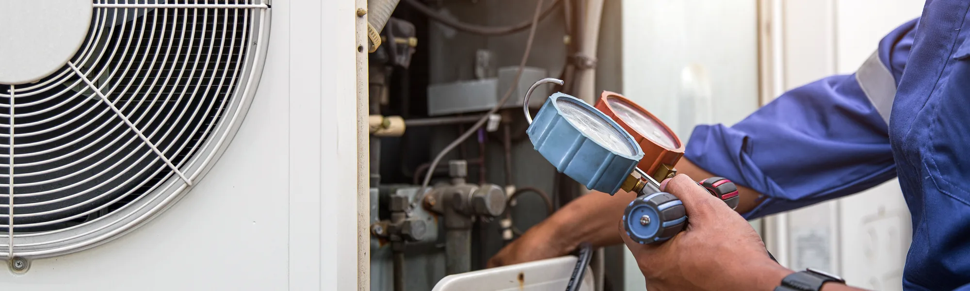 HVAC technician checking refrigerant pressure with manifold gauges
